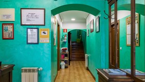 A hallway with green walls, wooden flooring, and framed documents on the walls. - Single Room 20 in Somo (Somo)