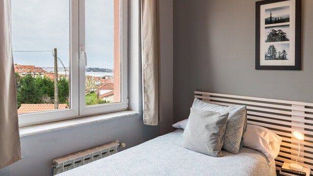 A bedroom with a bed, a window, a radiator, and a framed picture on the wall. - Single Room 20 in Somo (Somo)