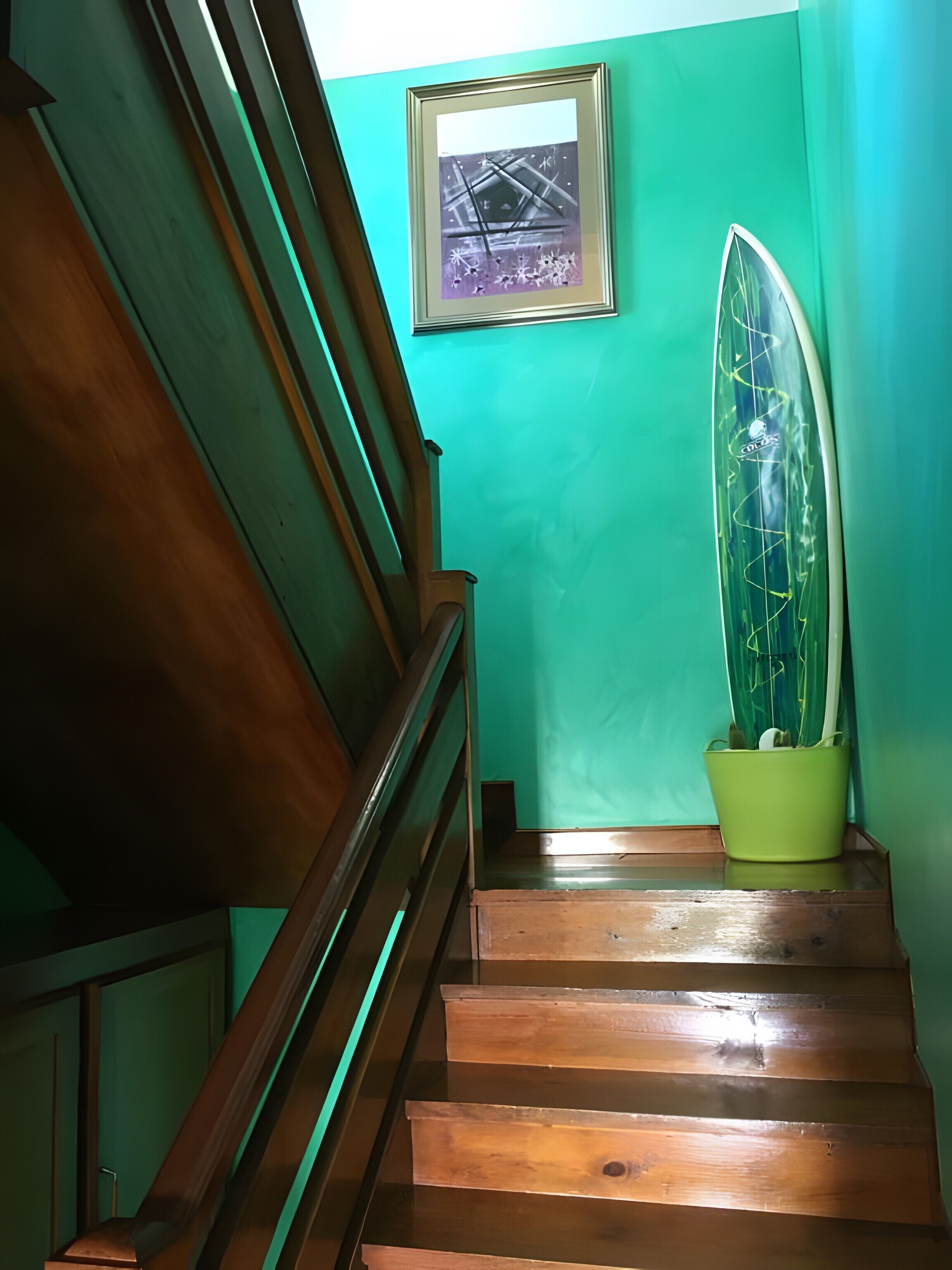 A wooden staircase with a green wall and a framed picture above it.