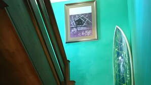 Un escalier en bois, avec un mur vert et un tableau encadré au-dessus.