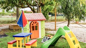 Un área de juegos infantiles con una casita, un tobogán y una mesa con bancos.
