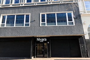 Un hotel llamado 'Nivara' con una fachada moderna, ventanas grandes y una puerta principal cerrada.
