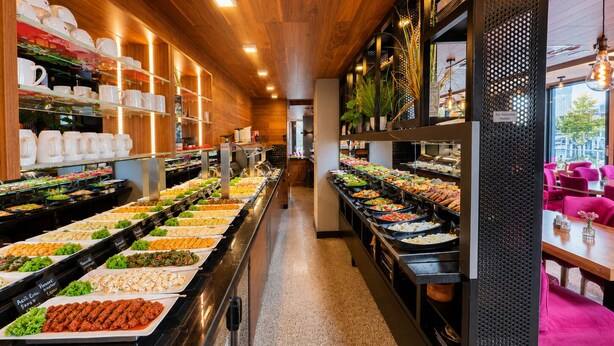 A buffet area with various food options, a coffee station, and seating area with tables and chairs. - Nivara Hotel (Hamburg)