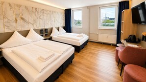 A hotel room with two beds, a TV, a coffee machine, and a view of the city. - Nivara Hotel (Hamburg)
