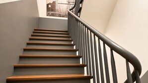 A staircase with wooden steps and a black metal handrail. - Nivara Hotel (Hamburg)