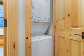 Ein Waschraum mit einer Frontlader-Waschmaschine und einem Trockner, Holzwänden und einer Tür mit einem Metallgriff.