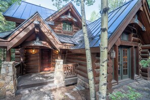 A log cabin with a stone foundation, a wooden porch, and a metal roof. - Summit Cabin - Luxury 3 BDR Condo w/ Sweeping Views (Telluride)
