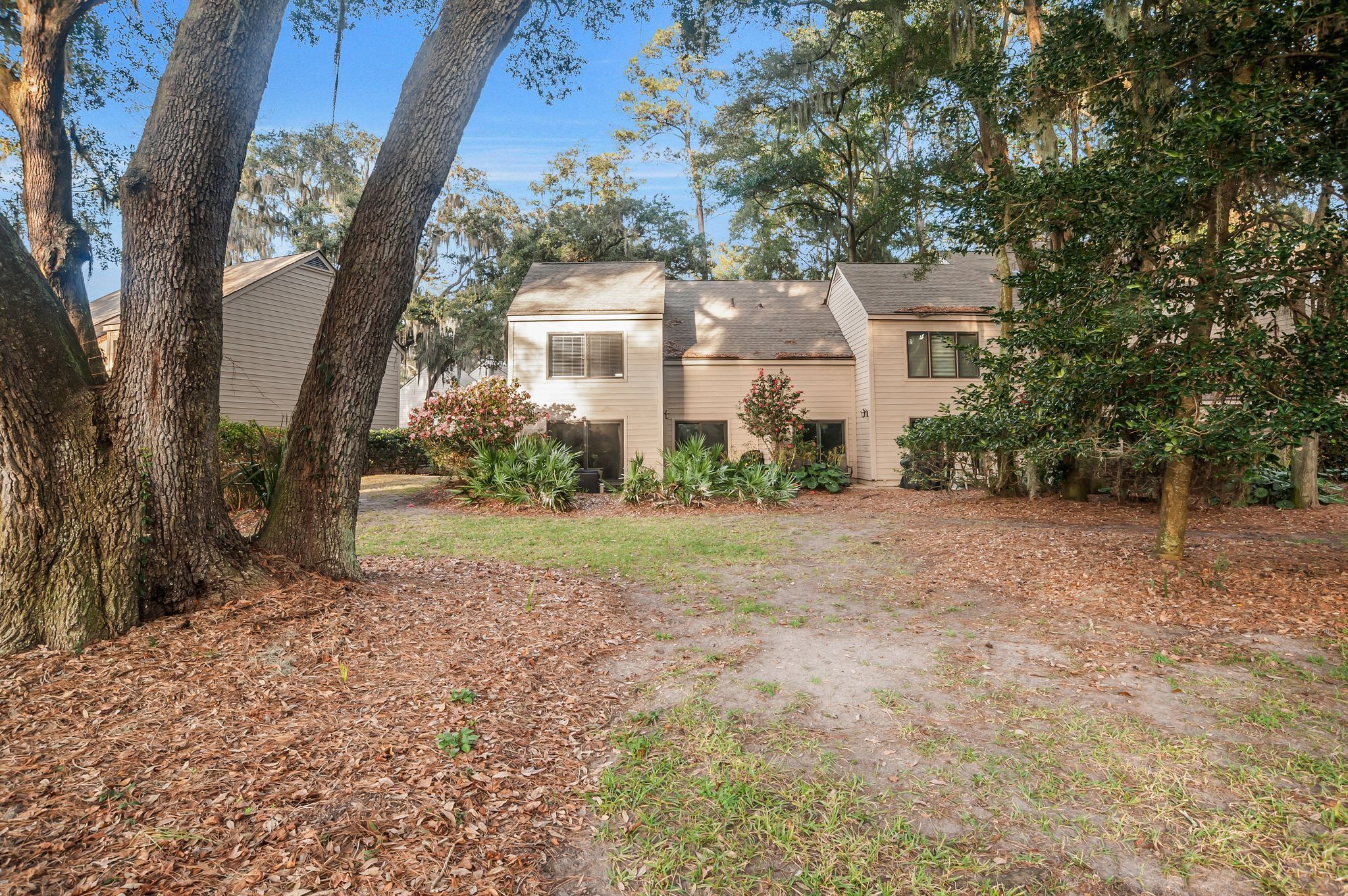 A residential property with a two-story house, a front yard with a lawn, and mature trees.