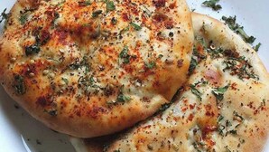 Un piatto bianco con due fette di pane piatto condite con erbe e spezie.