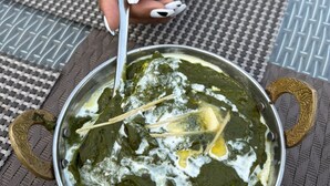 Una ciotola di spinaci con un cucchiaio, posata su un sottotavolo intrecciato.