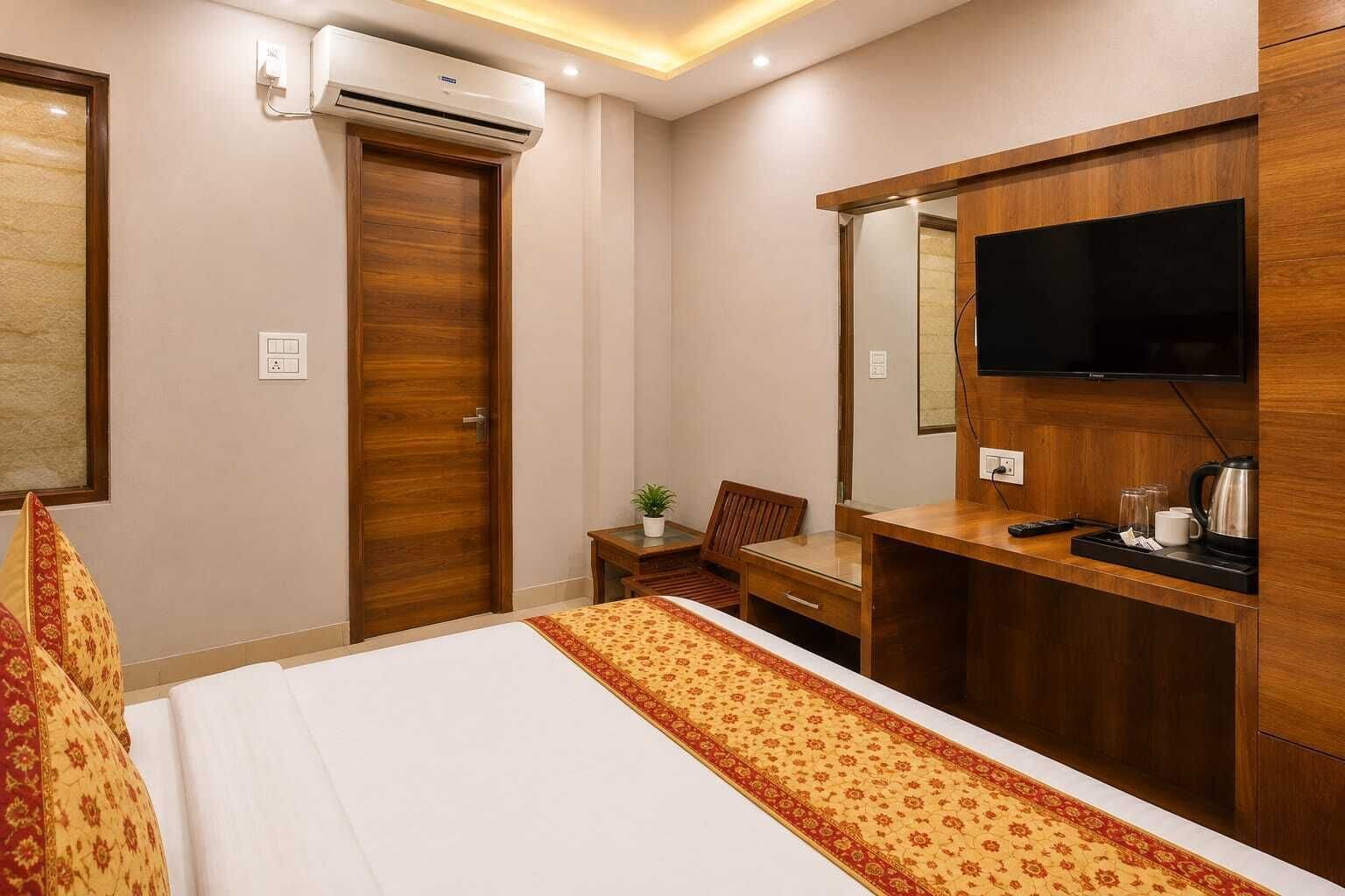 A hotel room with a bed, a desk, a chair, a television, and a wardrobe.