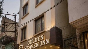 Esterno del Golden Heaven Inn, con un ingresso ben visibile con gradini che conducono alla porta, piante in vaso e una vista chiara dell'interno attraverso la facciata in vetro.