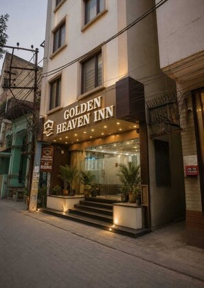 The exterior of the Golden Heaven Inn, featuring a prominent entrance with steps leading up to the door, potted plants, and a clear view of the interior through the glass facade. - Hotel Golden Heaven Inn Amritsar (Amritsar)
