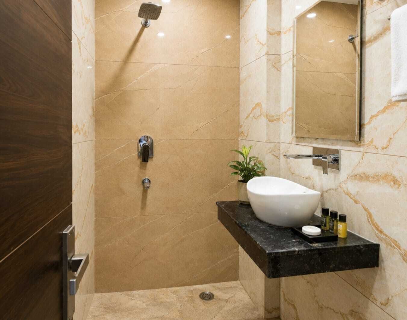 A modern bathroom with a marble floor, a freestanding bathtub, a sink with toiletries, and a shower.