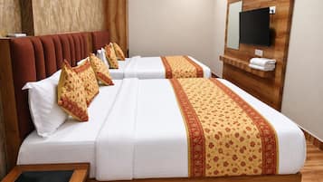 A hotel room with two beds, a wooden headboard, a flat-screen TV mounted on the wall, and a wooden floor.