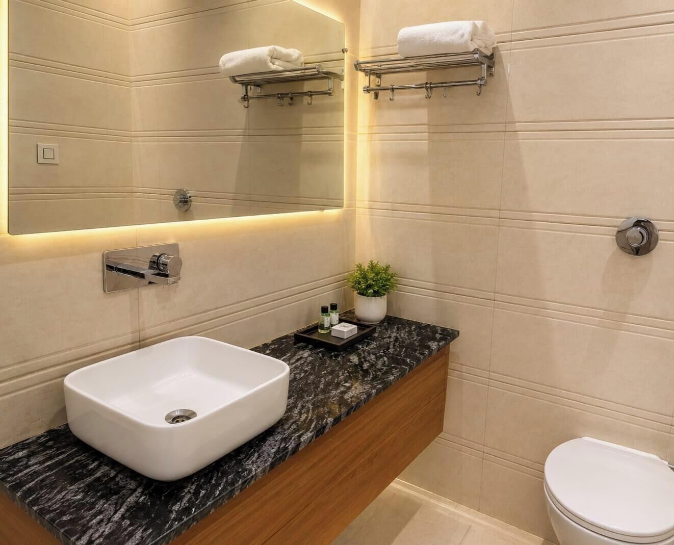 Een moderne badkamer met een marmeren aanrecht, een witte wastafel, een spiegel en een toilet.