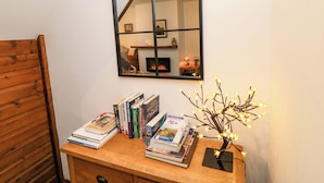 A wooden desk with books and a small tree with lights, a mirror, and a fireplace in the background. - Cliffe Cottage (Saltburn-by-the-Sea)