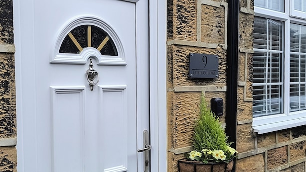 A white door with a decorative glass panel, a mailbox, and a number plate indicating '9'. - Cliffe Cottage (Saltburn-by-the-Sea)