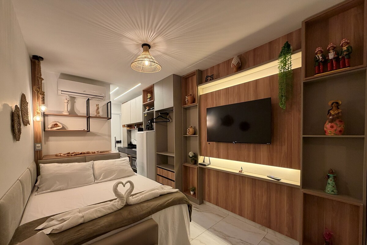 Une chambre moderne avec un lit, un téléviseur fixé au mur et des étagères intégrées ornées d’objets décoratifs.