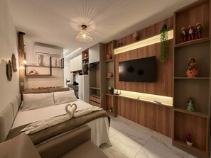 A modern bedroom with a bed, a television mounted on the wall, and built-in shelving with decorative items. - Waikiki Garden - Porto de Galinhas (Ipojuca)