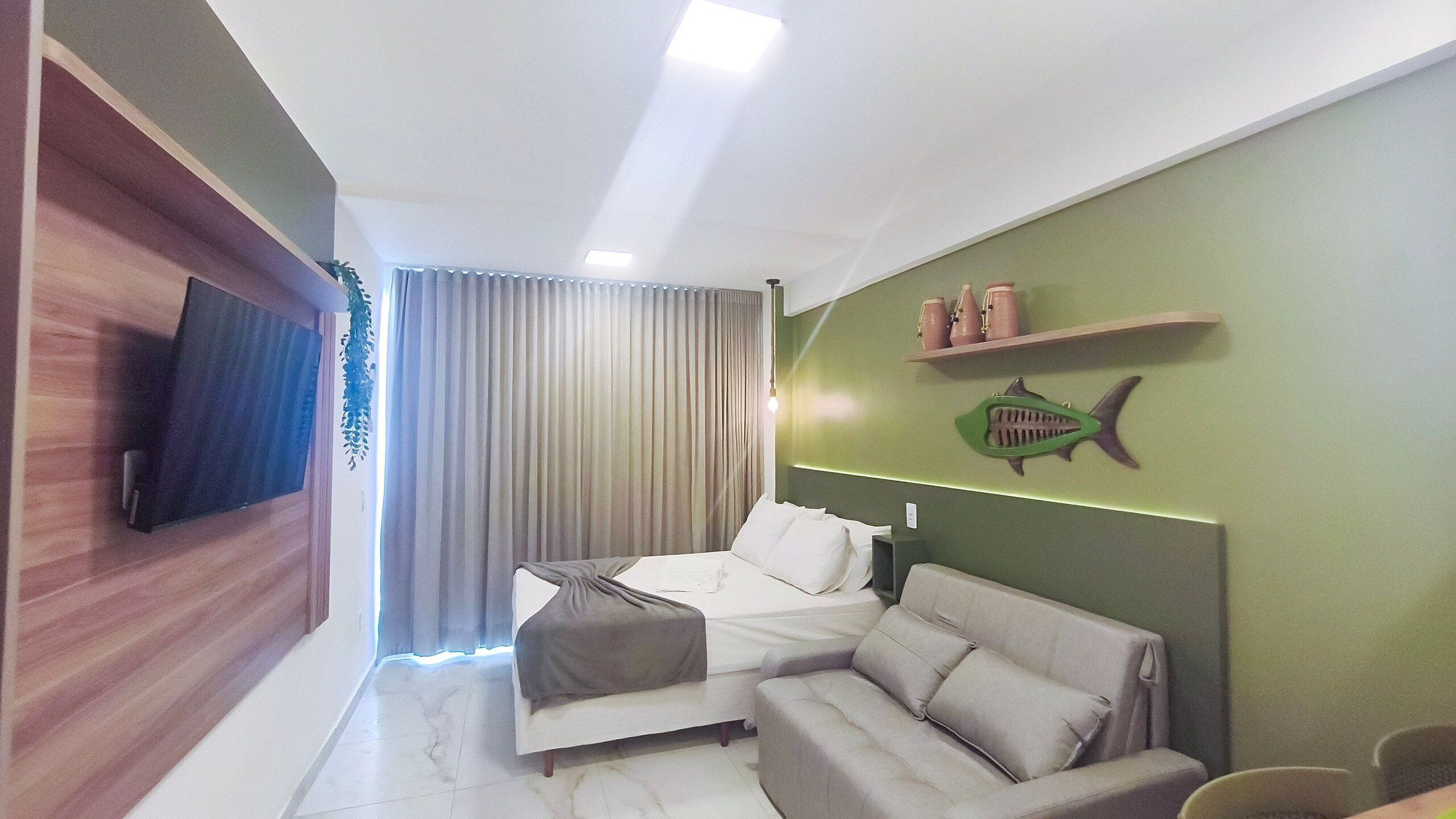 Une chambre d’hôtel moderne, équipée d’un lit, d’un canapé, d’une télévision et d’un mur d’accent de couleur verte.