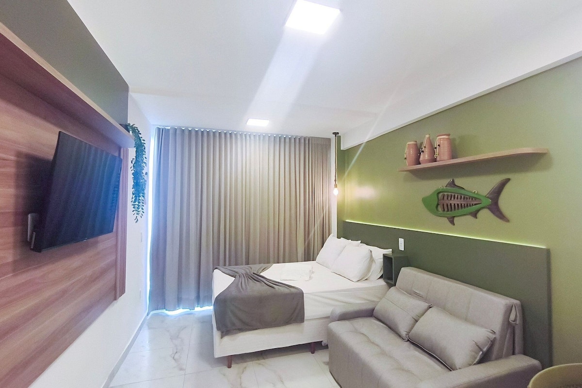 Une chambre d’hôtel moderne, équipée d’un lit, d’un canapé, d’une télévision et d’un mur d’accent de couleur verte.