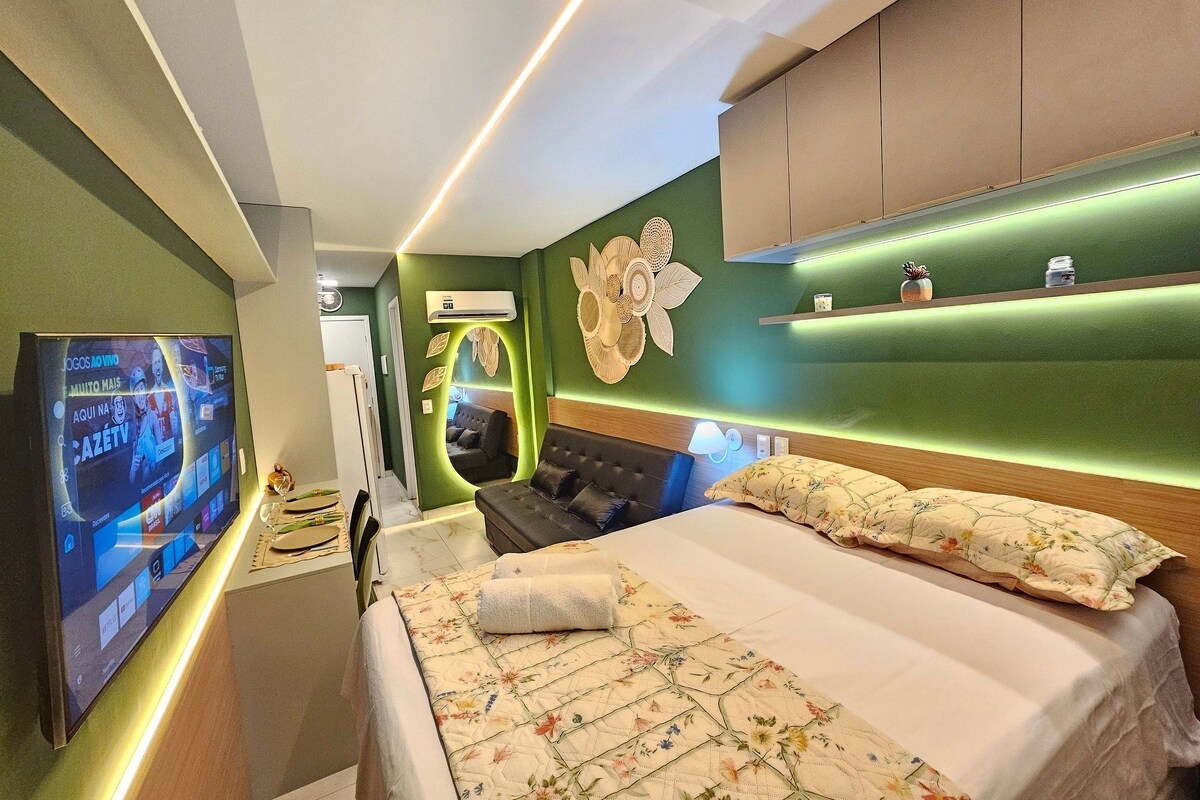 Une chambre d’hôtel équipée d’un lit, d’une télévision, d’un canapé et d’une étagère fixée au mur.