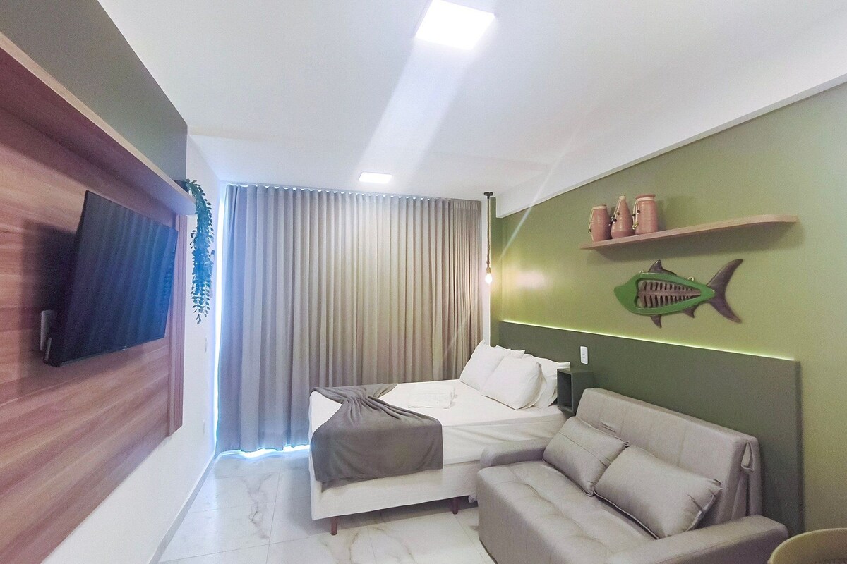 Une chambre d’hôtel moderne, équipée d’un lit, d’un canapé, d’une télévision et d’un mur d’accent de couleur verte.