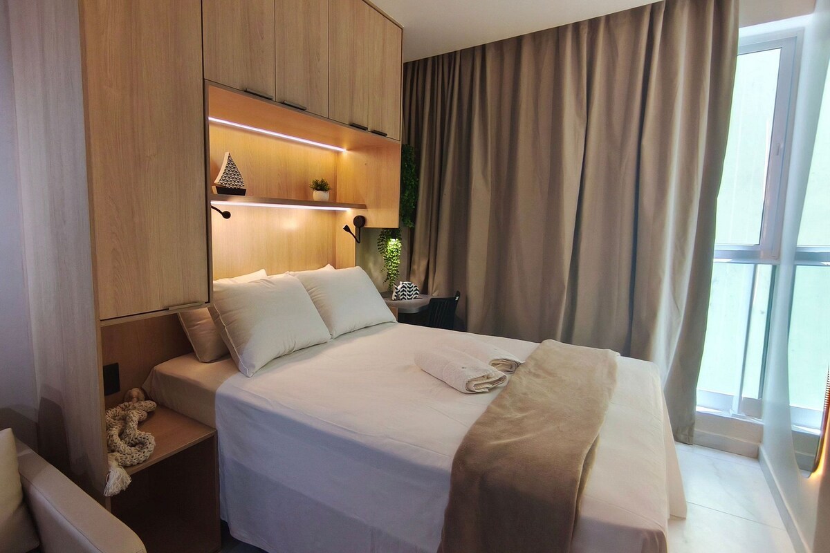 Une chambre d’hôtel avec un lit, une table de chevet et une fenêtre avec des rideaux.