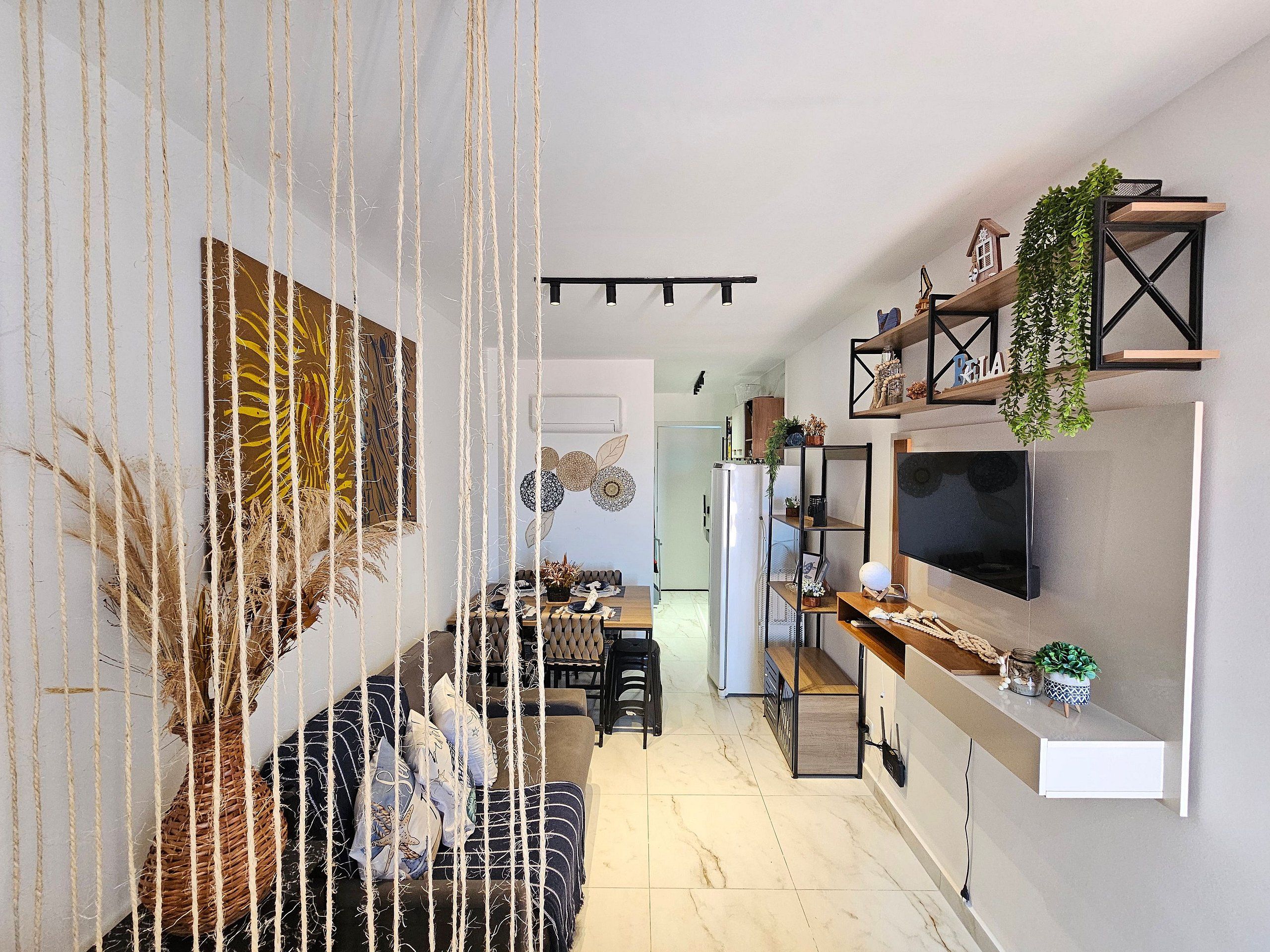 A modern living room with a sofa, a dining area, and a kitchen with a TV.