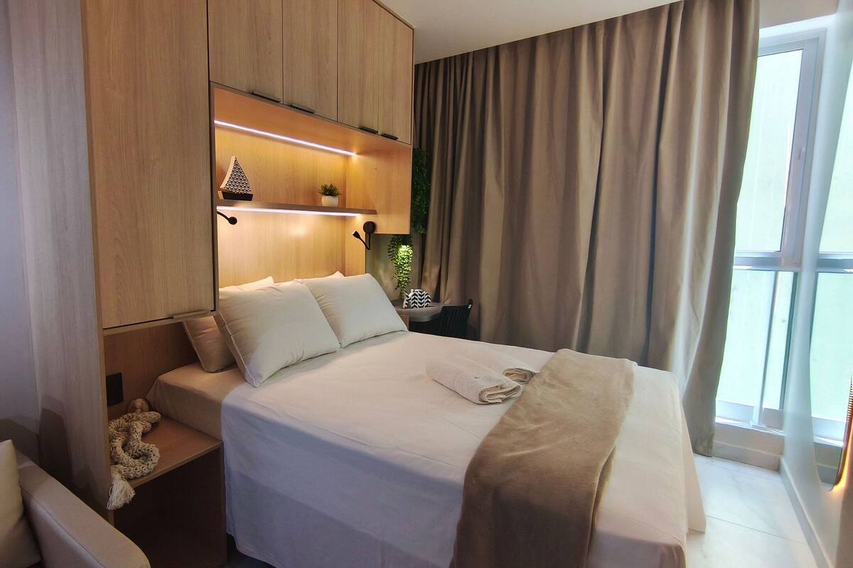 Une chambre d’hôtel avec un lit, une table de chevet et une fenêtre avec des rideaux.