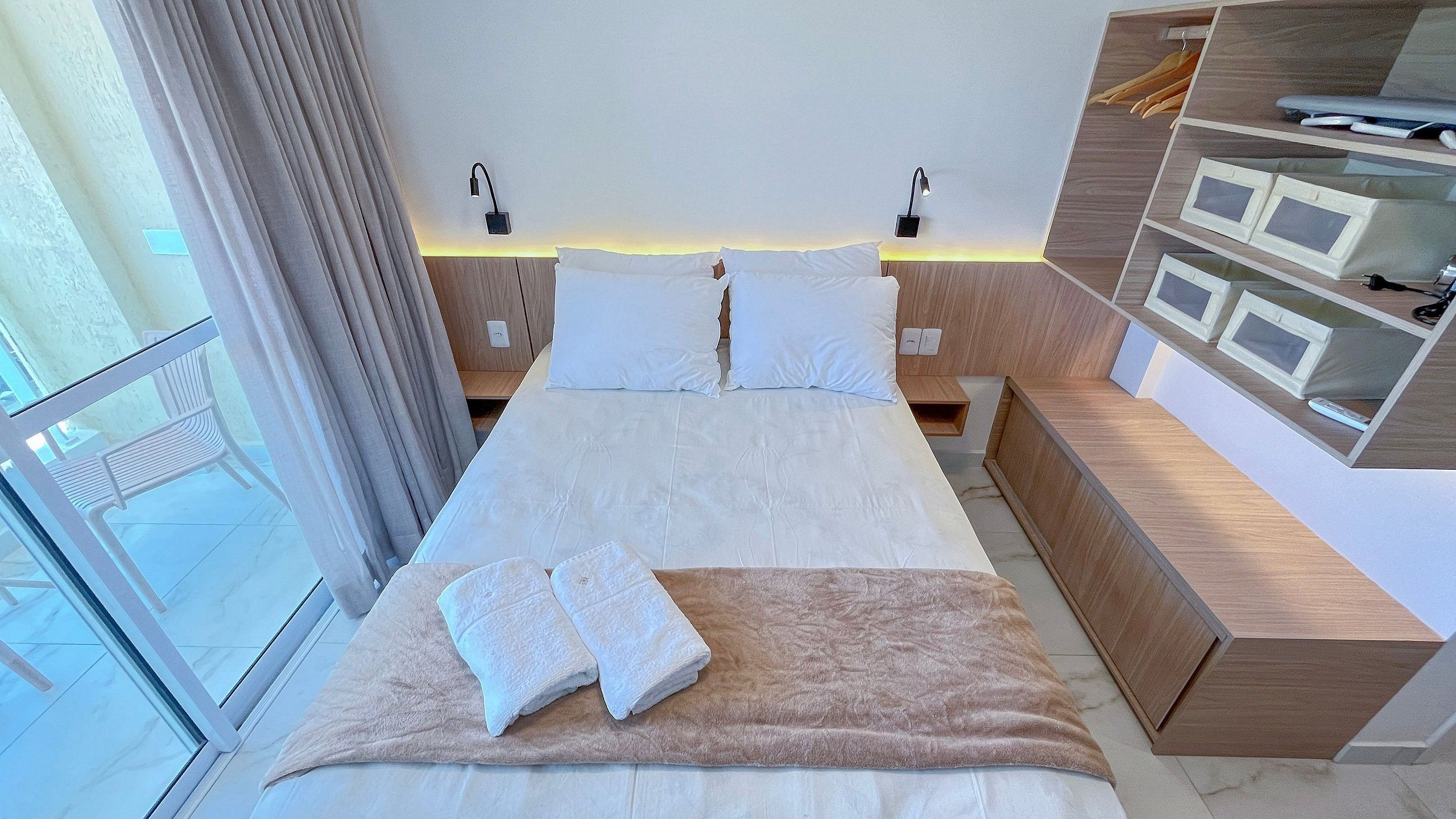 Een moderne hotelkamer met een groot bed, nachtkastjes, een inbouwkast en een balkon.