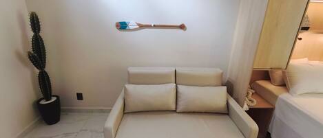 A minimalist room with a bed, a potted cactus, and two wall-mounted objects.