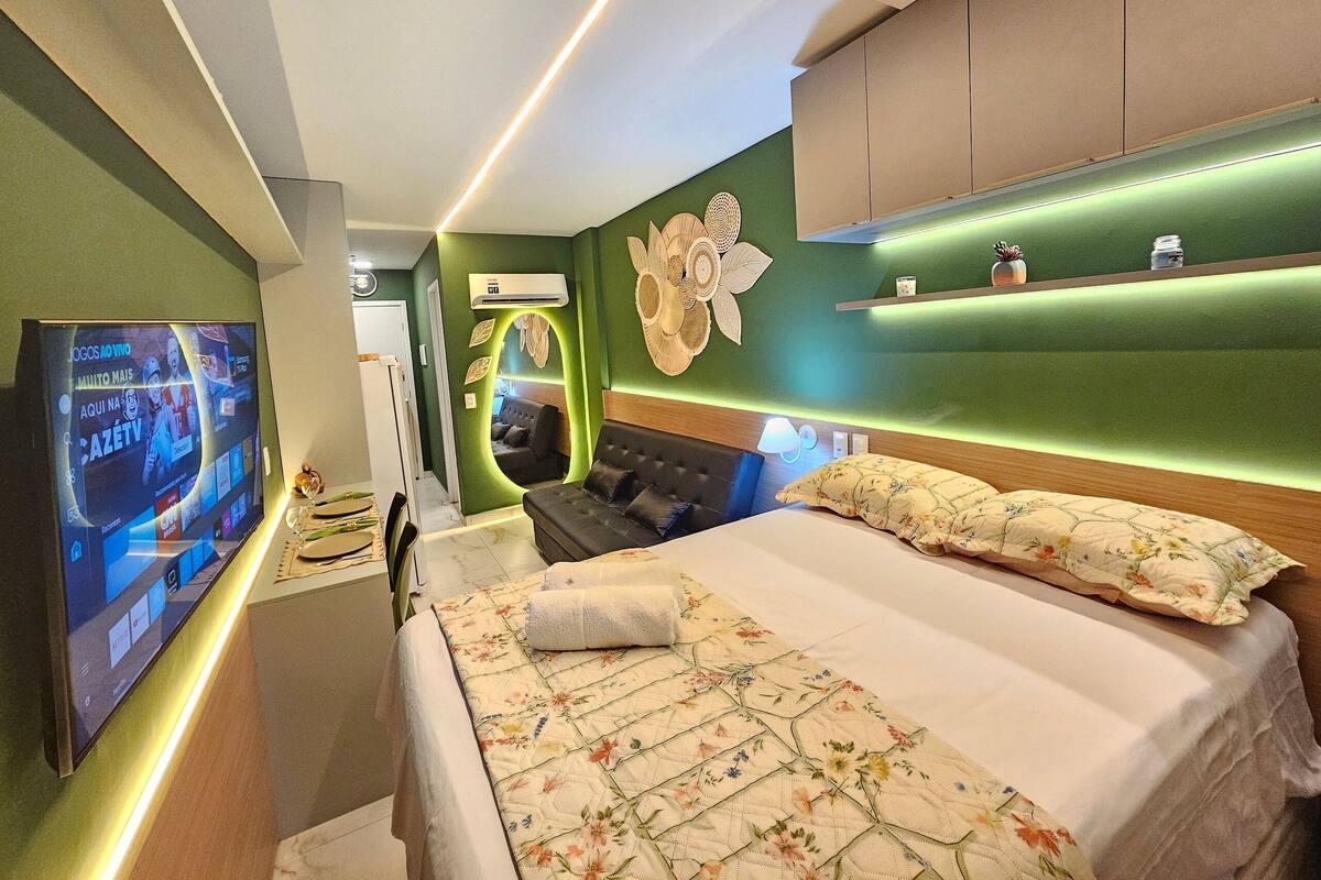 Une chambre d’hôtel équipée d’un lit, d’une télévision, d’un canapé et d’une étagère fixée au mur.