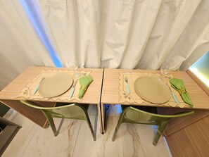 Een eettafel met twee stoelen, een placemat en servies.