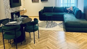 En moderne stue med fiskebensparketgulv, en modulsofa, et spiseområde med et rundt bord og stole samt kunst på væggene.