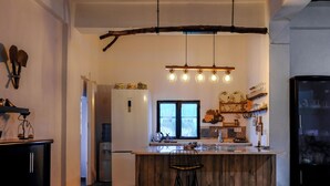 A rustic kitchen with a wooden island, hanging light fixtures, and a large window. - Saygın Farmhouse Ephesus Boutique Hotel (Tire)