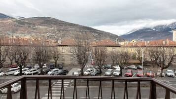A parking lot with cars, a mountain in the background, and buildings with red roofs.