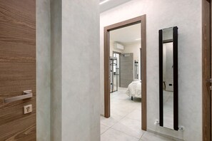 A hallway with a wooden door, a mirror, and a bed in the background. - Double Room - MyAostaProject with Mountain View, Wi-Fi and Air Conditioning (Aosta)