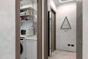A laundry area with a washing machine, microwave, and shelves with toiletries. - Double Room - MyAostaProject with Mountain View, Wi-Fi and Air Conditioning (Aosta)