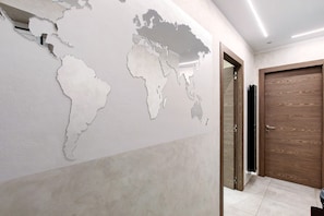 A hallway with a world map mural, a wooden door, and a tiled floor. - Double Room - MyAostaProject with Mountain View, Wi-Fi and Air Conditioning (Aosta)