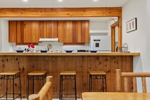 Eine Küche mit Holzschränken, einer weißen Arbeitsplatte und Barhocker.
