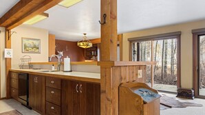Una cocina con armarios de madera, un lavamanos y una zona de comedor con un tapete.