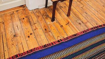 Uma cadeira de madeira com almofada azul estampada em um quarto com piso de madeira e paredes brancas.