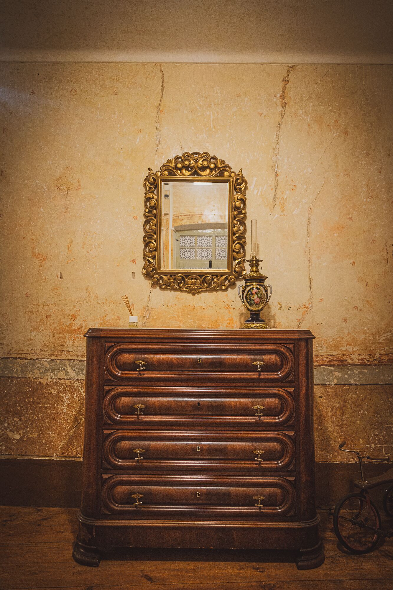 A wooden dresser with multiple drawers and a mirror above it, set against a textured wall.