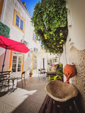 An outdoor seating area with tables, chairs, and a red umbrella. - Very Typical - Alojamento Local (Elvas)