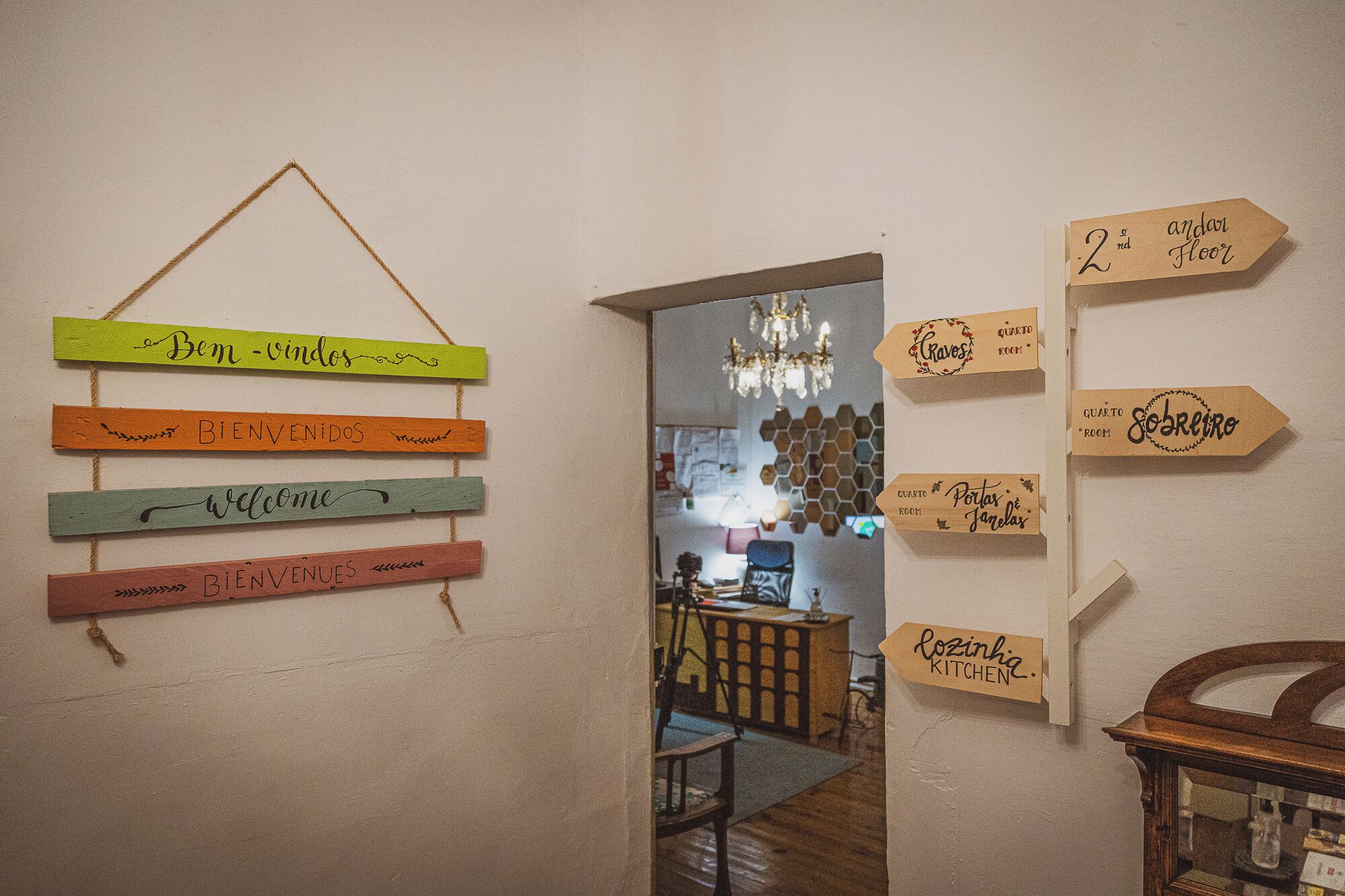 Corredor com placas indicando a direção para a cozinha e placas com nomes de quartos.