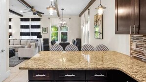A kitchen with granite countertops, dark cabinetry, and pendant lighting. - Villa Soleil Dunes (Miramar Beach)