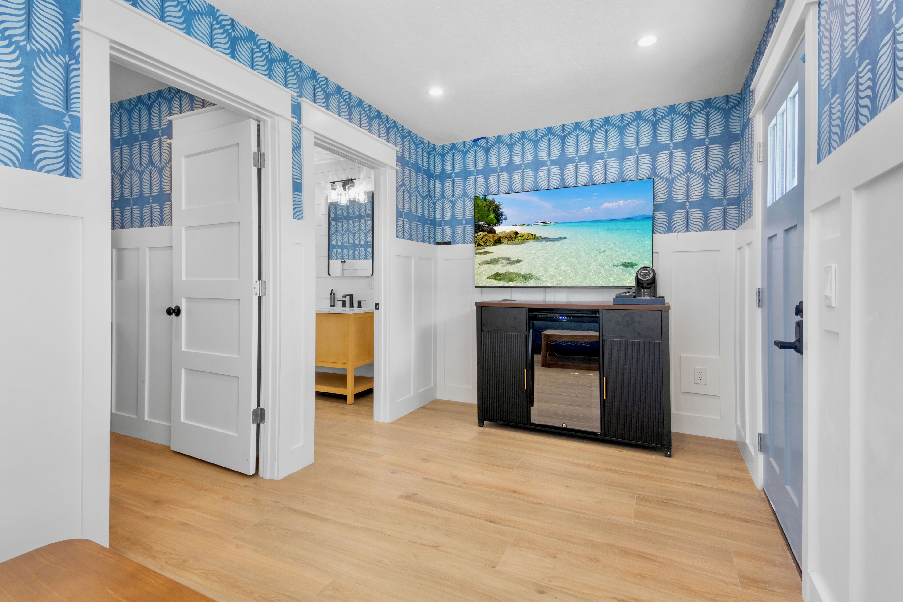 Ein Zimmer mit Holzboden, einem Fernseher auf einem Schrank und einer Tür zu einem anderen Raum.