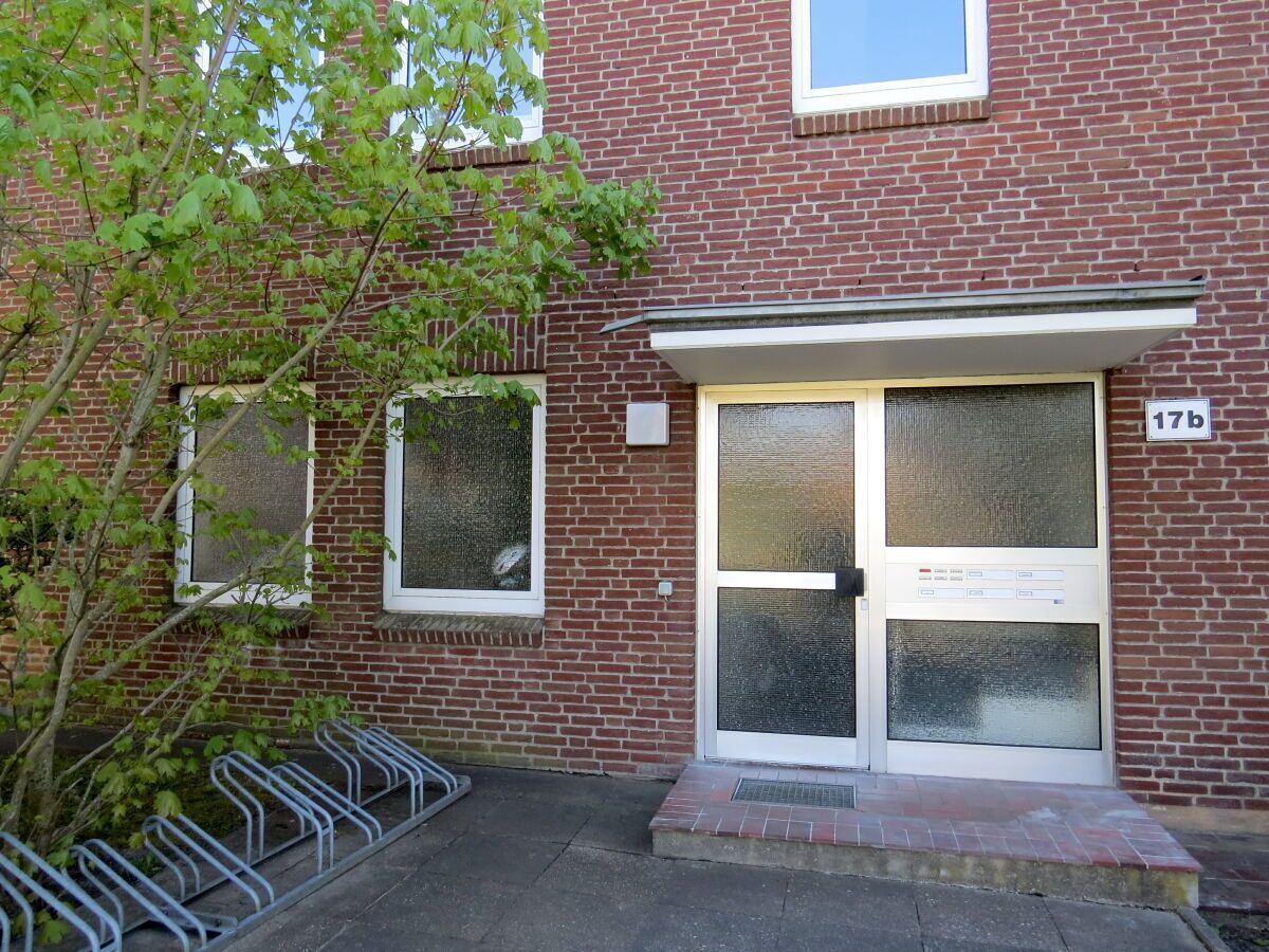 Un edificio de ladrillo con entrada por un doble puerta, una ventana pequeña y un letrero con el número '17b'.